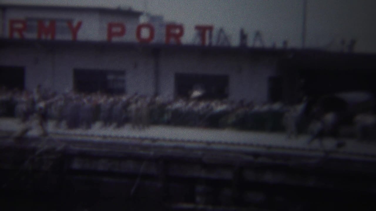 Yokohama, Japan, 1954 frame showing partial ARMY PORT signage, a crowd, parked cars, and foreground brass instruments.