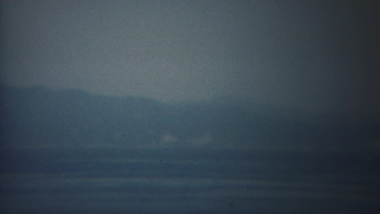 Hazy blue water and distant shoreline under a muted sky.