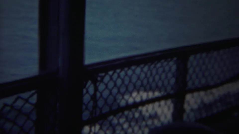 A dark vertical post and chain-link railing appear in the foreground of a 1954 Yokohama sea view.