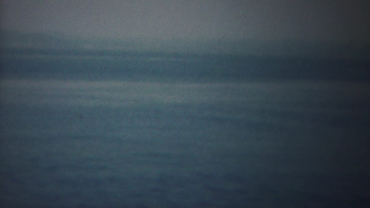 Soft horizon line over dark water, divided by a vertical film join.