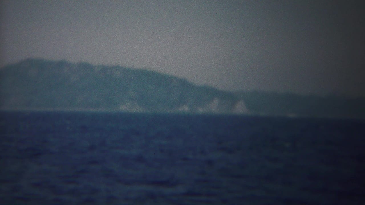 1954 8mm view near Yokohama, Japan, showing dark open water and a soft, hazy shoreline on the horizon.