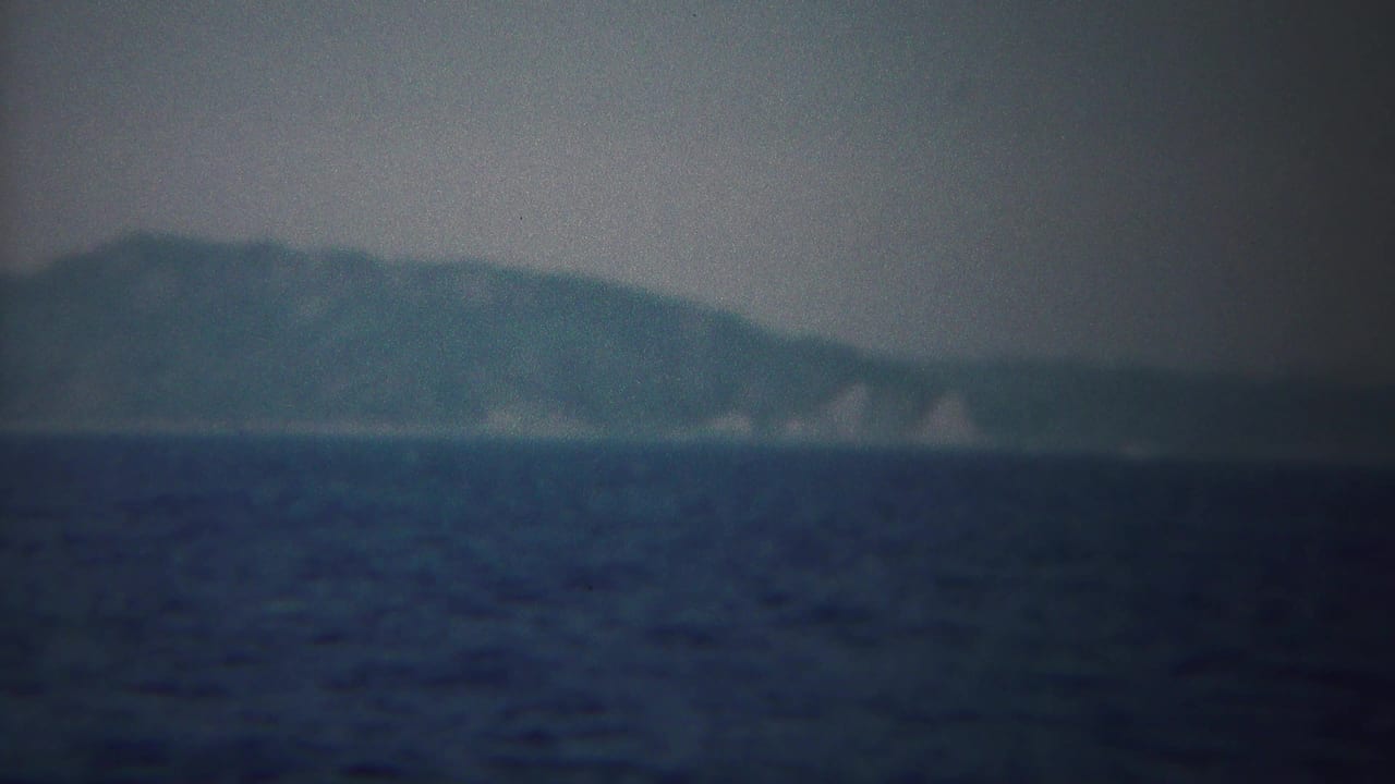 Soft 8mm frame of a distant landmass near Yokohama, with pale shoreline areas visible beyond the open sea.