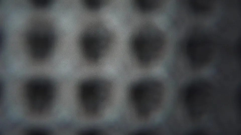 1954 Yokohama 8mm frame with rows of dark rounded holes or pits on a grey patterned field, seen in shallow focus.