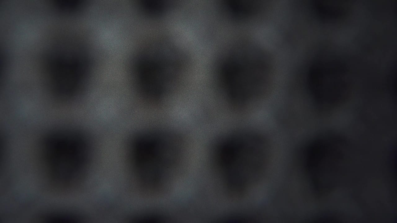 1954 Yokohama 8mm frame showing a close abstract surface with dark pits, grey-blue tones, grain, and uneven focus.