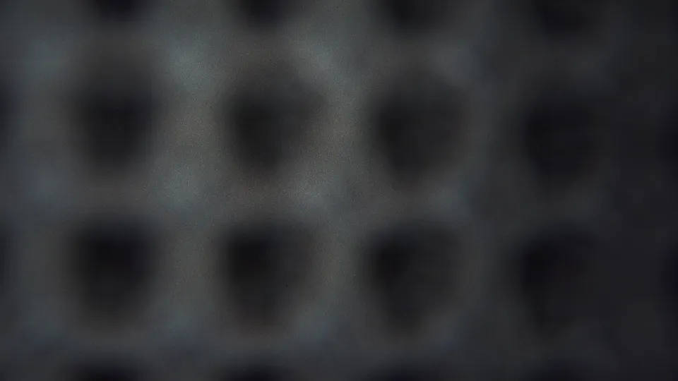 1954 Yokohama 8mm frame showing a close abstract surface with dark pits, grey-blue tones, grain, and uneven focus.