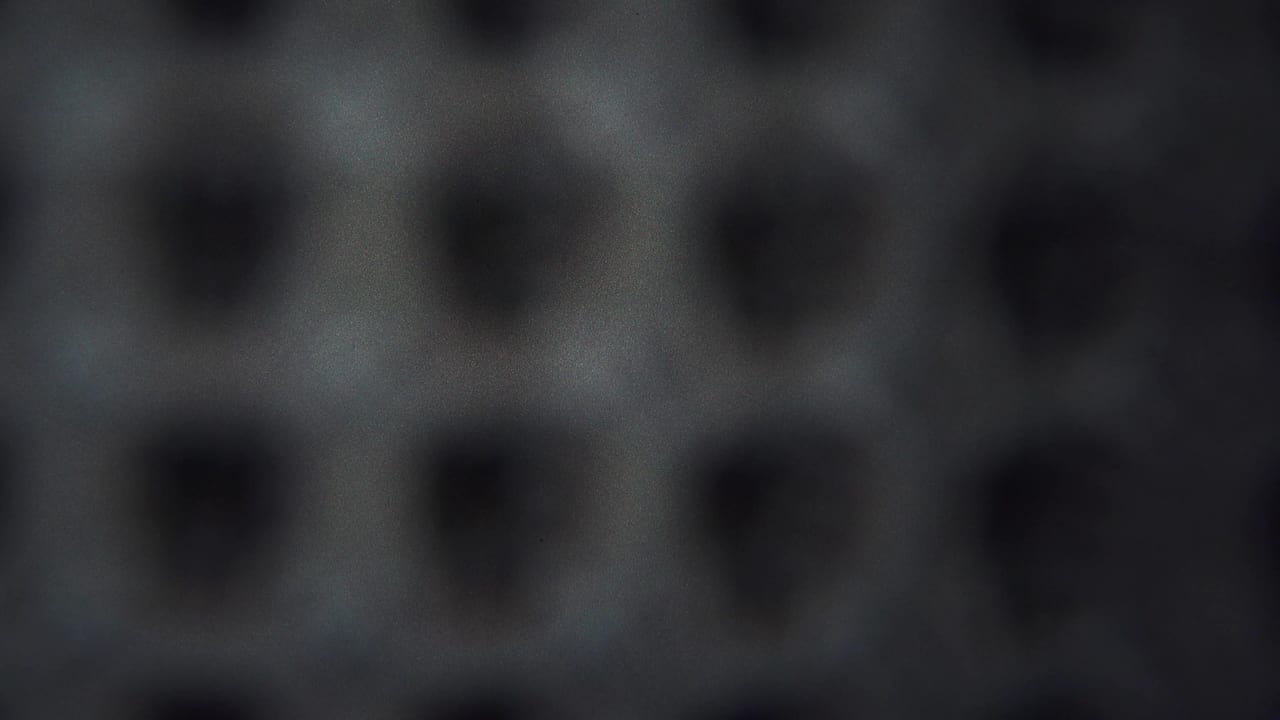 1954 Yokohama 8mm frame of an abstract grey field with repeated dark depressions, subdued exposure, and visible film texture.