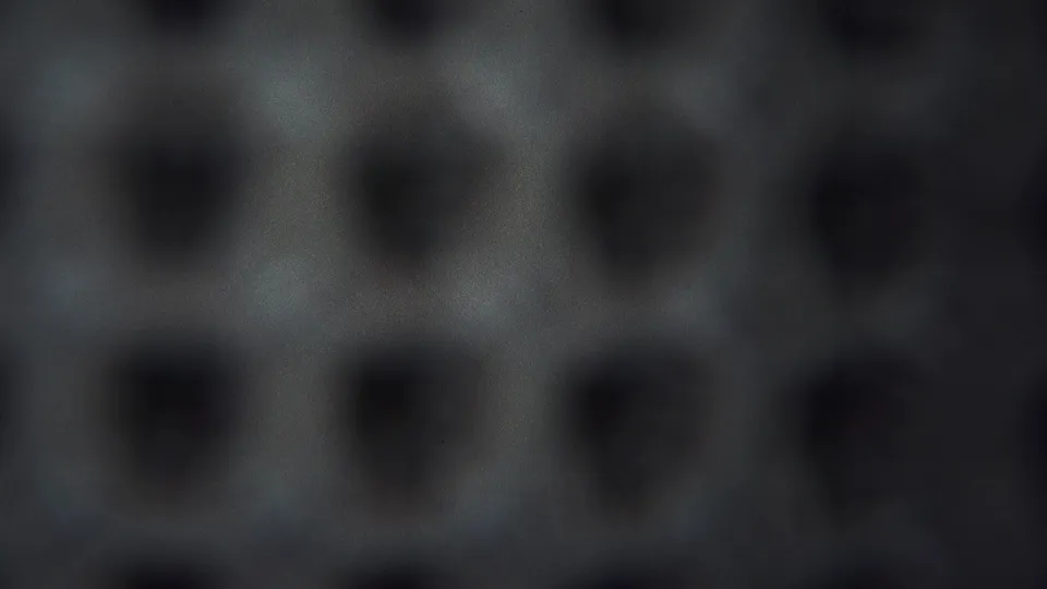 1954 Yokohama 8mm frame of an abstract grey field with repeated dark depressions, subdued exposure, and visible film texture.