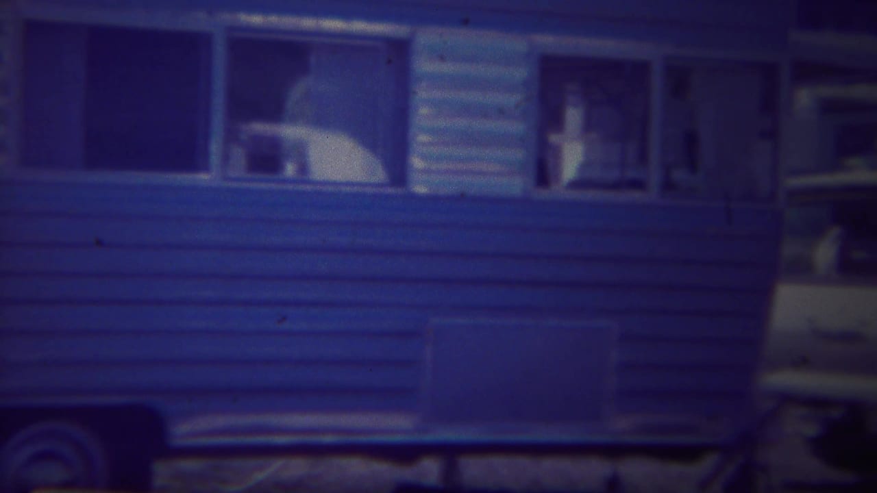 Side of a blue travel trailer with open windows and a door.