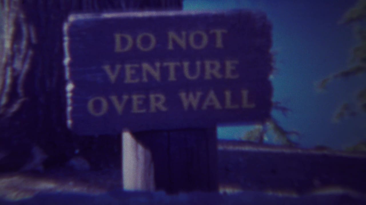 Wooden sign reading DO NOT VENTURE OVER WALL beside trees and an overlook edge.