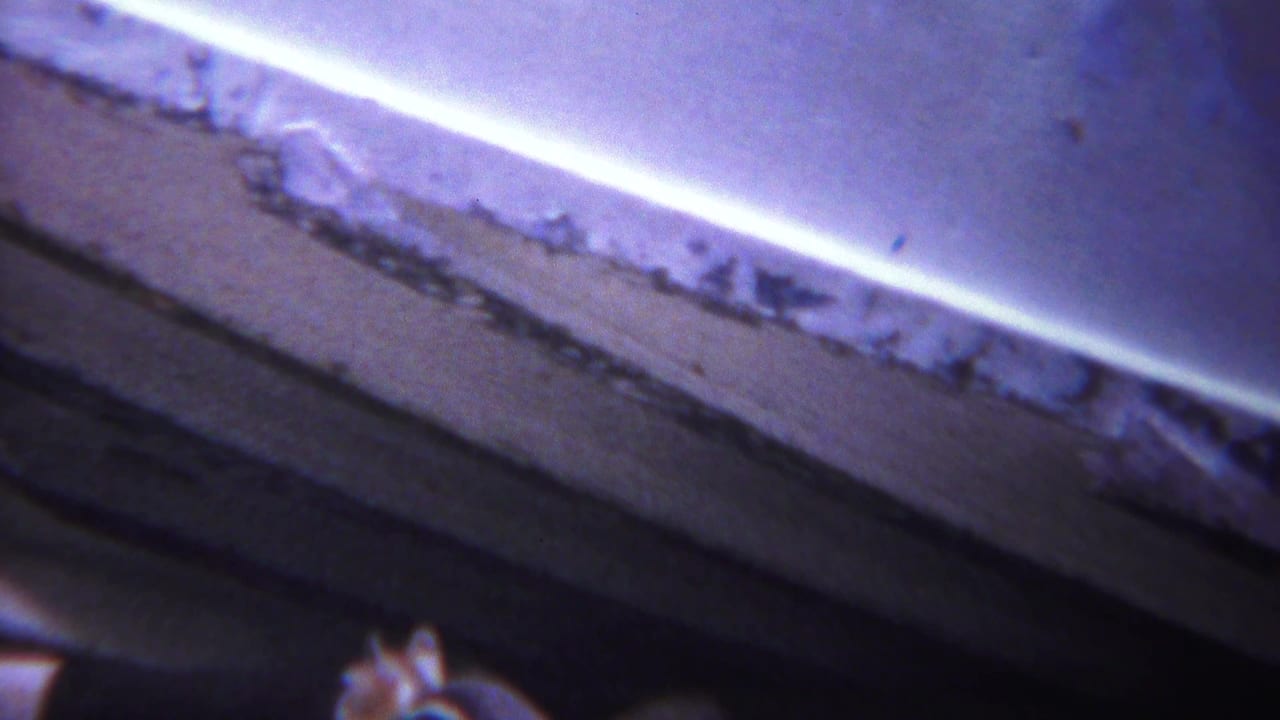 Close view of a pale worn edge beside a dark rough surface.
