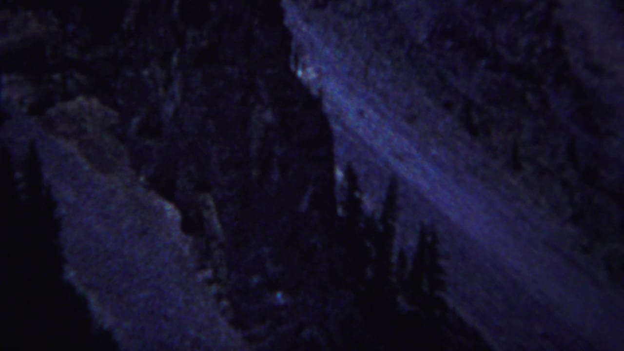 Dark blue rock formations with conifer silhouettes in low light.