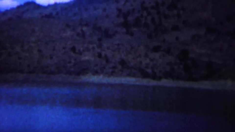 A blue lake and rocky hillside appear in a 1967 Yellowstone scenic view from the same home-movie clip.