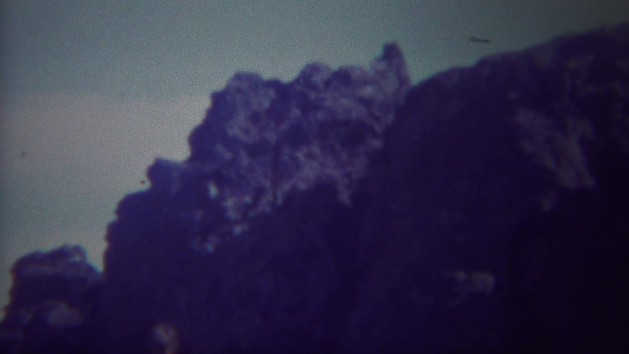 Large dark rock mass silhouetted against a washed pale sky.
