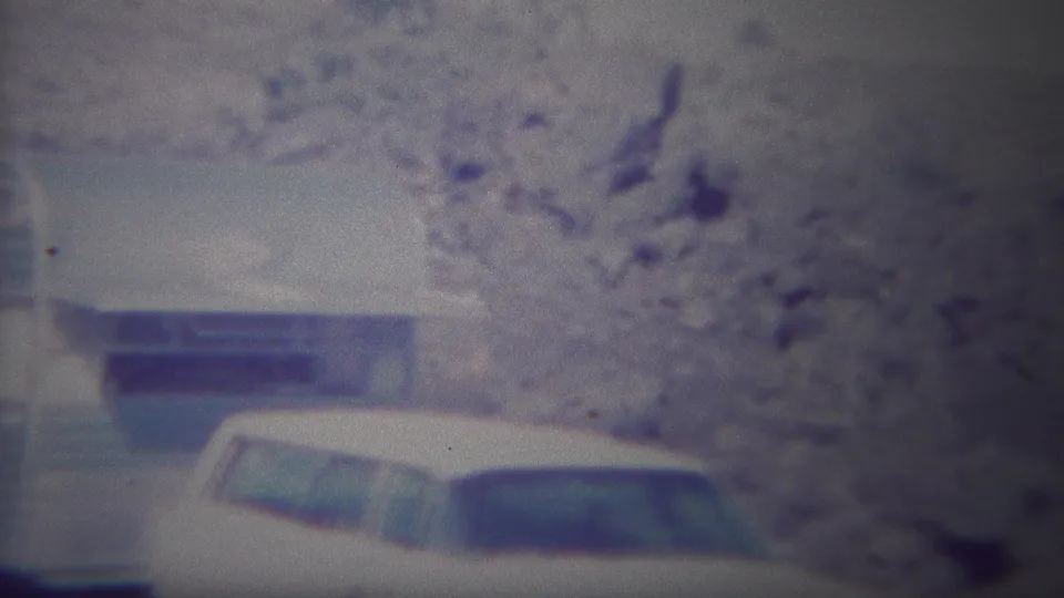 1967 Yellowstone home-movie frame showing a light blue and white camper trailer with a white station wagon parked beside it.