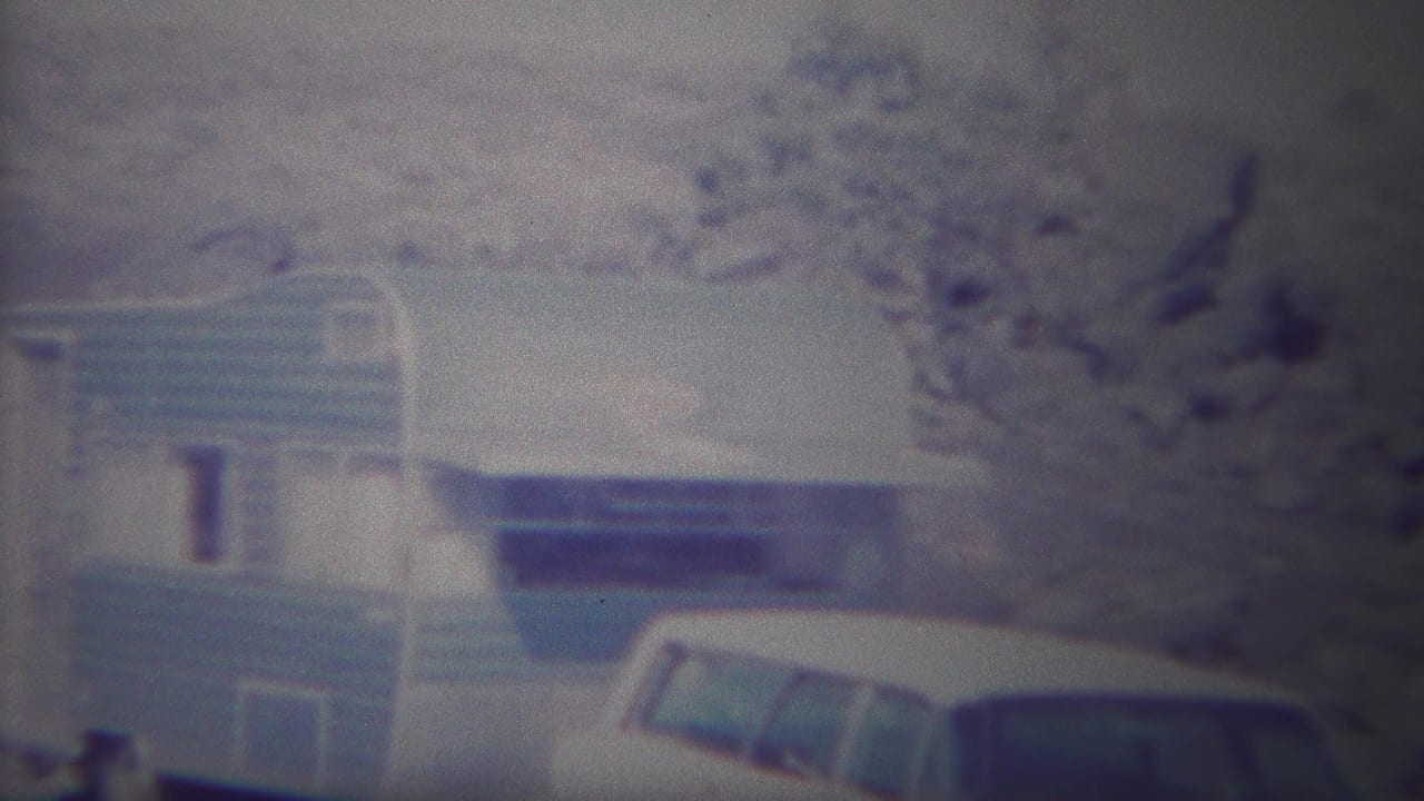 Home-movie frame from Yellowstone, Wyoming, showing the camper trailer centered with the parked station wagon at the lower right.
