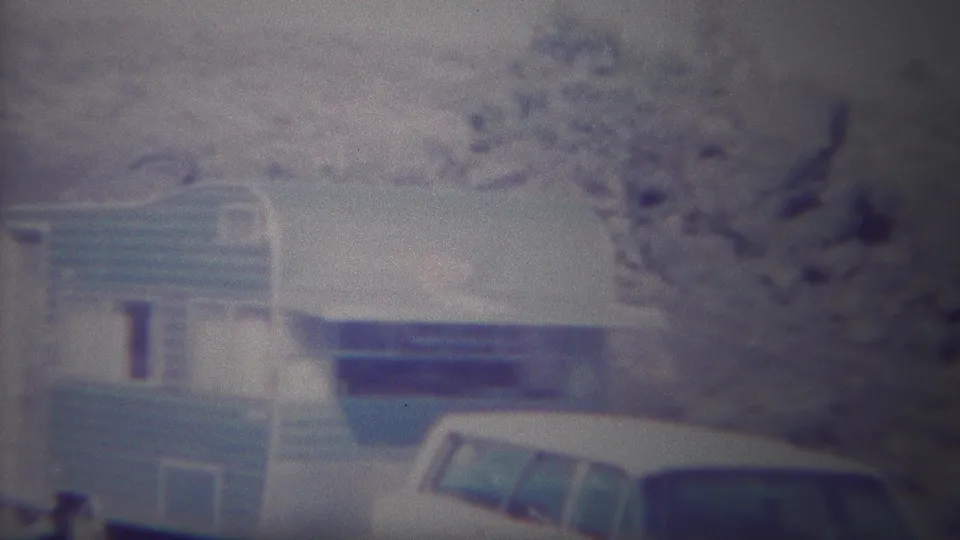 Home-movie frame from Yellowstone, Wyoming, showing the camper trailer centered with the parked station wagon at the lower right.