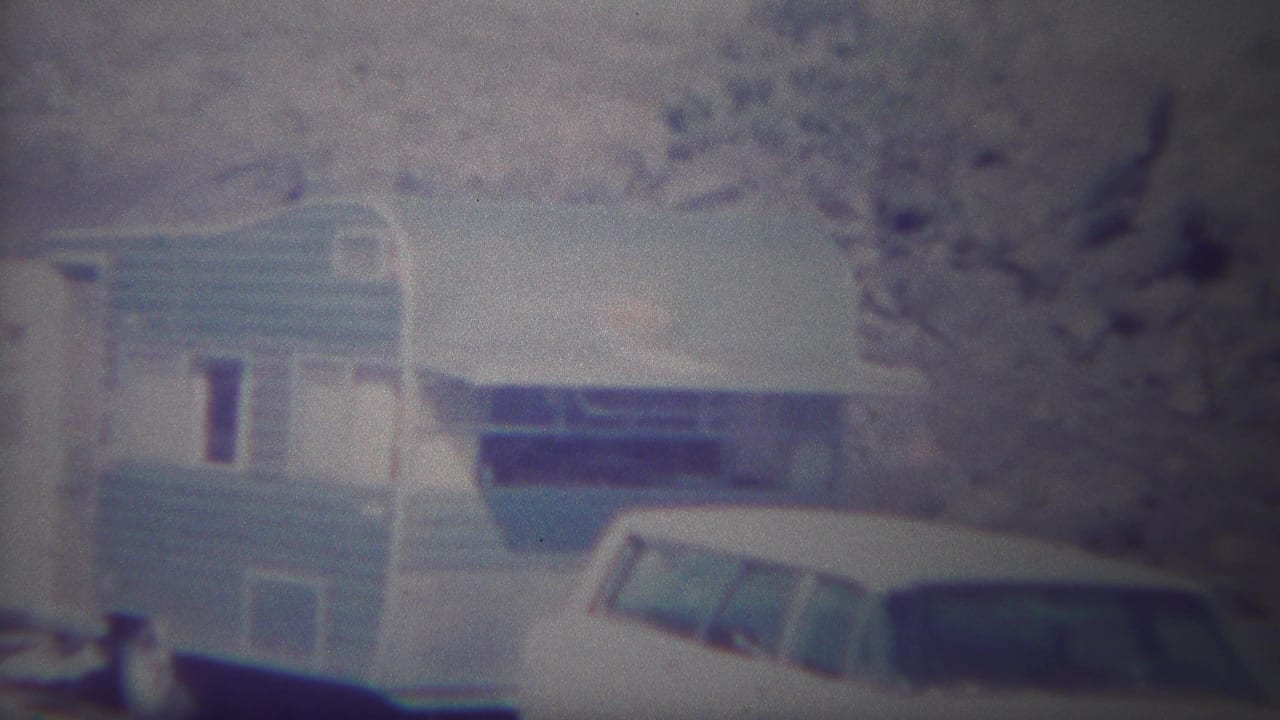 Blue-and-white camping trailer with a white vehicle partly visible in front.