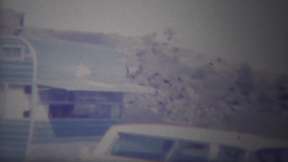 1967 Yellowstone home-movie frame showing the side of a blue-and-white trailer and a white vehicle partly obscuring the lower portion of the scene.