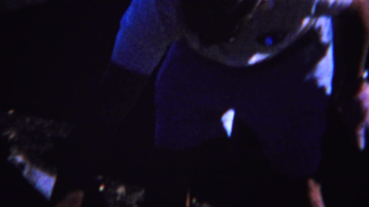 Two adults are partially visible in a very dark outdoor setting.