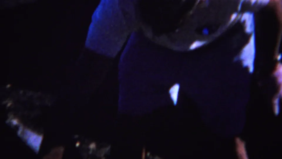 1967 Yellowstone-area home-movie frame with partially seen adults in dark clothing and strong blue-purple nighttime exposure.