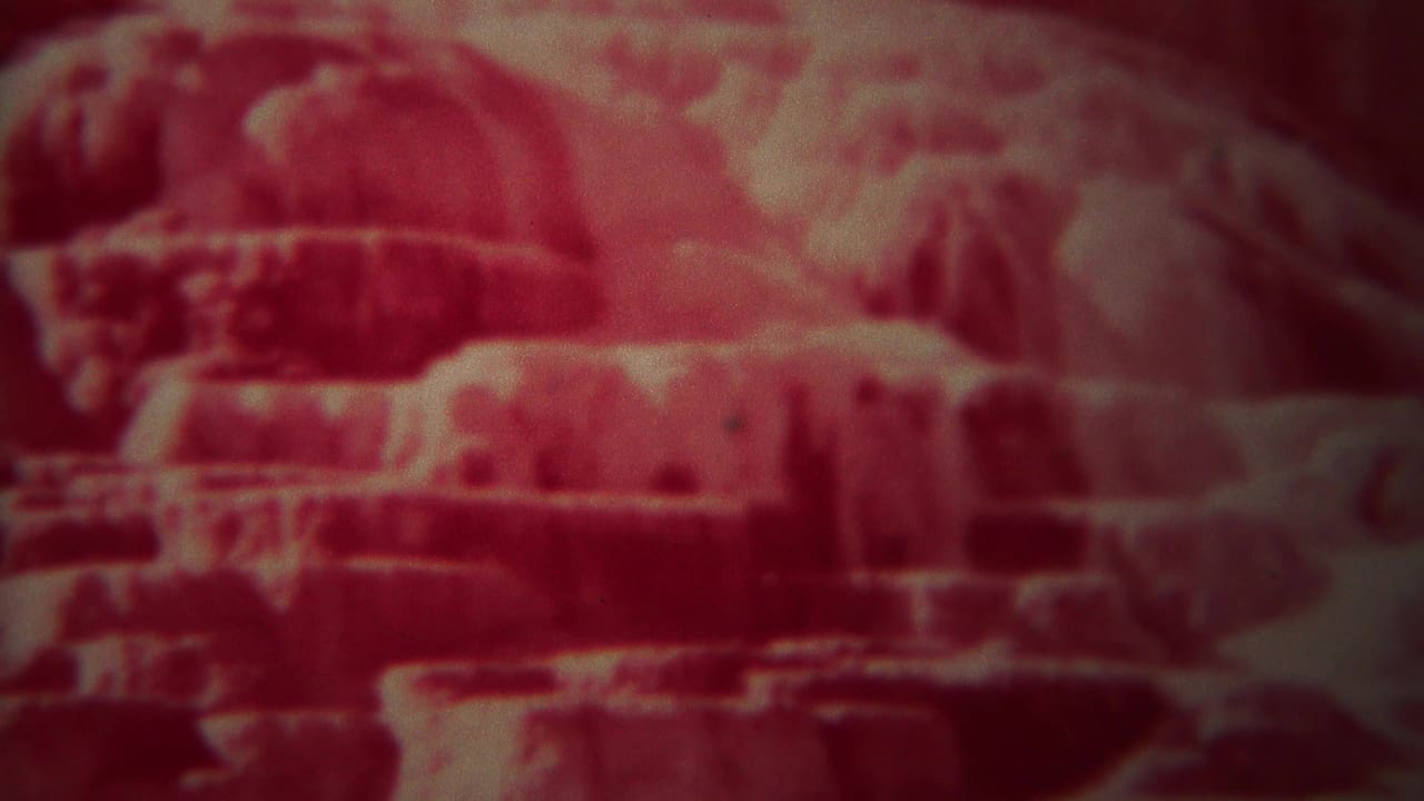 Red-tinted close view of layered rock ledges and shadowed recesses.