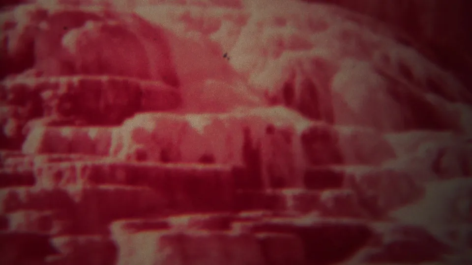 1967 Yellowstone frame with step-like geological ledges, pale mineral areas, and a heavy red film cast.