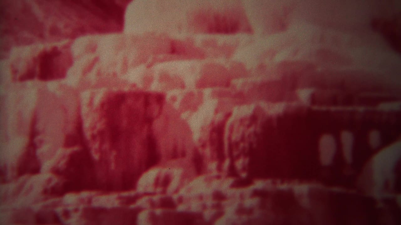 Red-faded 1967 Yellowstone home-movie frame showing rugged canyon terrain, soft focus, and heavy 8mm grain.