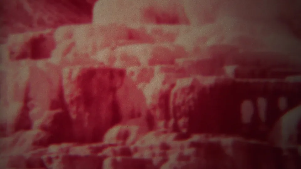 Red-faded 8mm frame from Yellowstone showing canyon rock formations in a soft, static visitor-shot view.