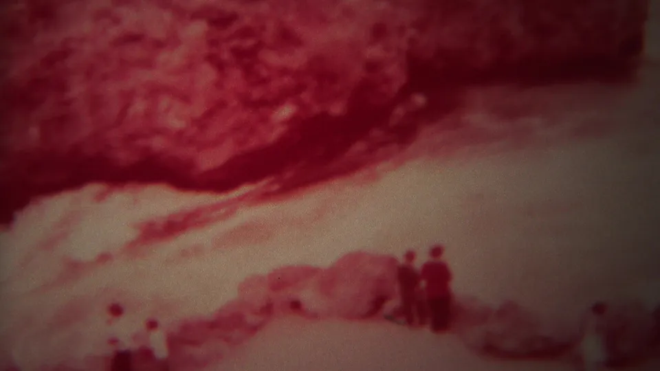1967 Yellowstone 8mm frame showing a rocky red bank, fast water, and a small indistinct group standing near the river.