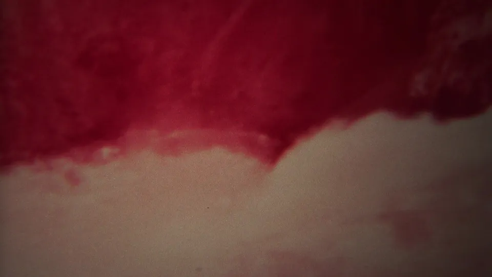1967 Yellowstone 8mm frame of abstract rushing water, with a red cast above a pale foamy lower edge.