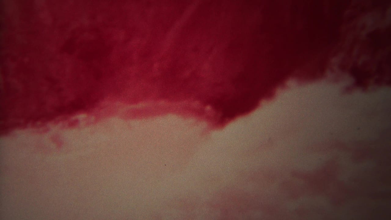 1967 Yellowstone 8mm frame showing red-pink rushing water and a lighter foamy surface, with grain and soft exposure.