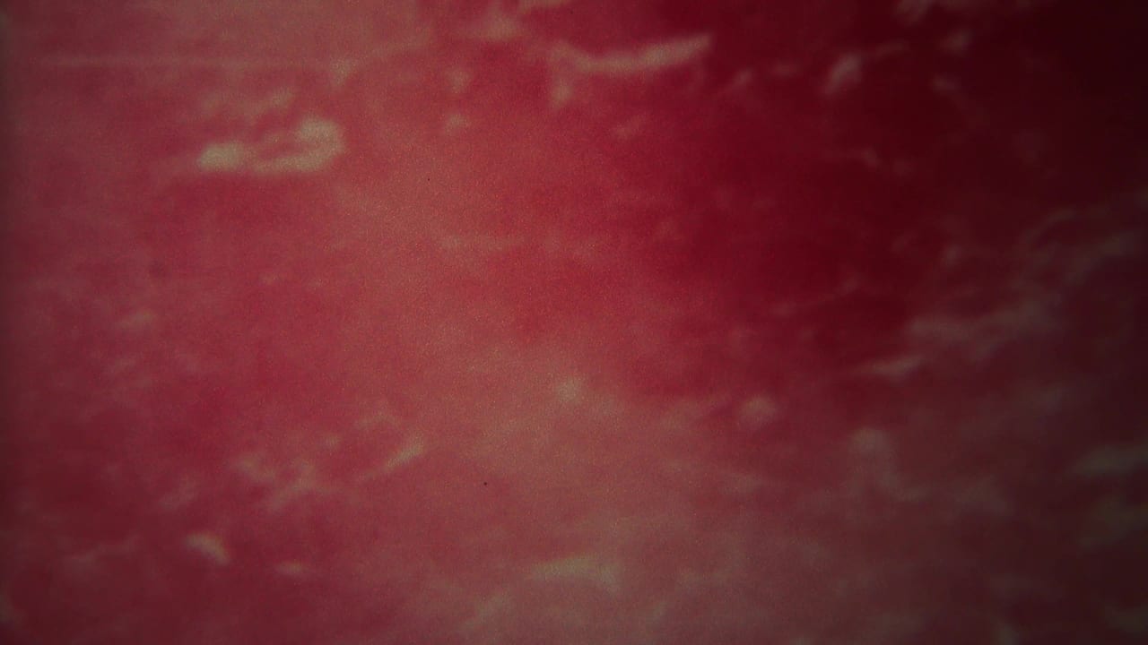Soft red and pink water surface with cloudy motion and dark edges.