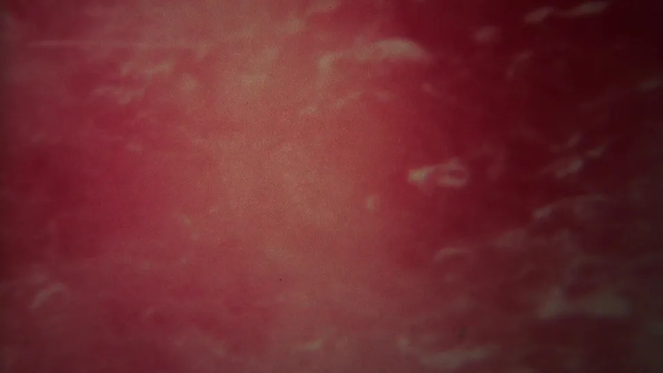 1967 Yellowstone 8mm frame showing moving pink-red water with pale foamy traces, dark edges, and home-movie grain.