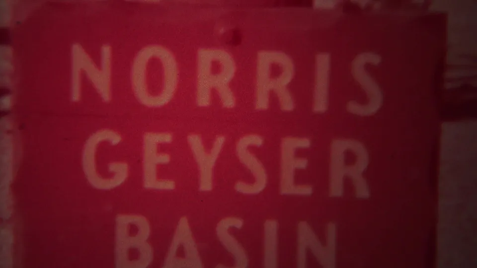 1967 Yellowstone home-movie frame showing a close, red-faded view of the Norris Geyser Basin sign.