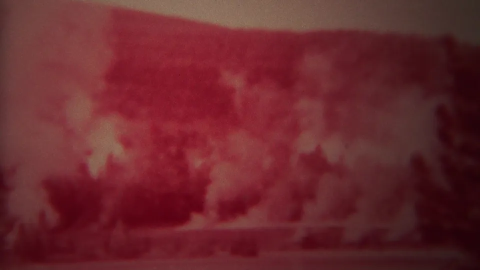 1967 Yellowstone 8mm frame showing red wildfire glow and smoke across a forested landscape with dark tree silhouettes.