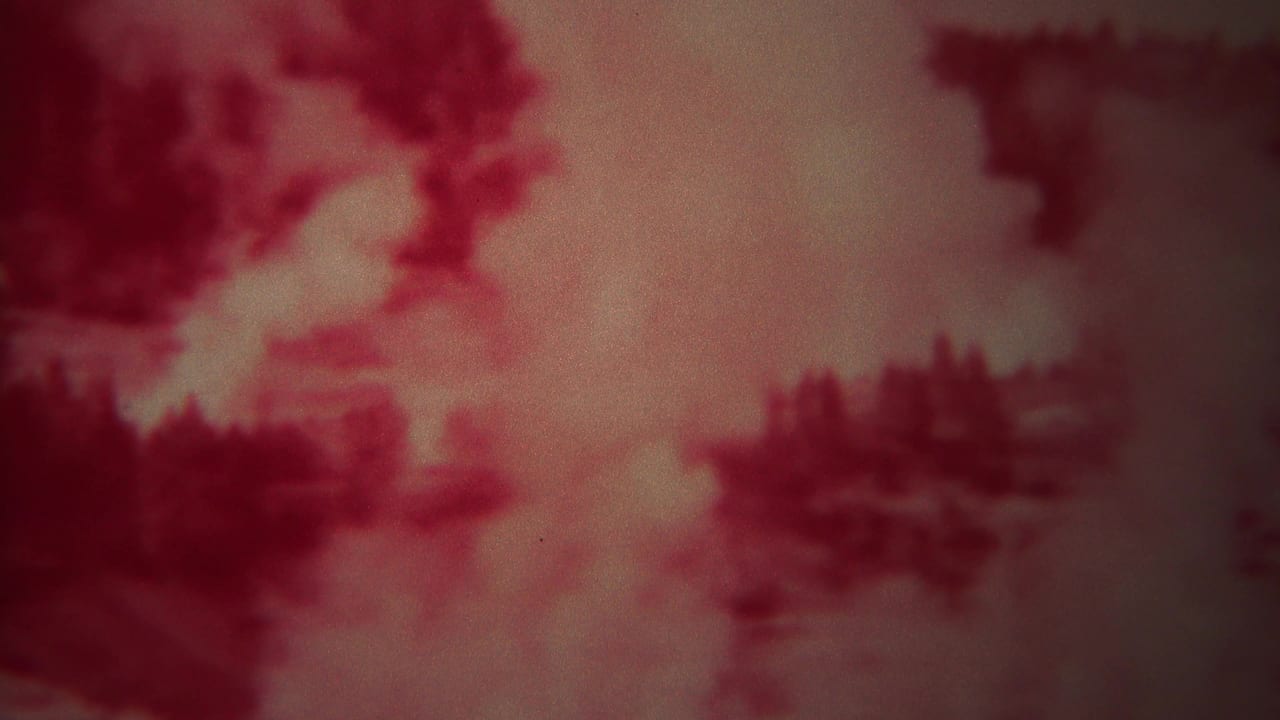 Soft red-tinted view of blurred geothermal landscape forms.