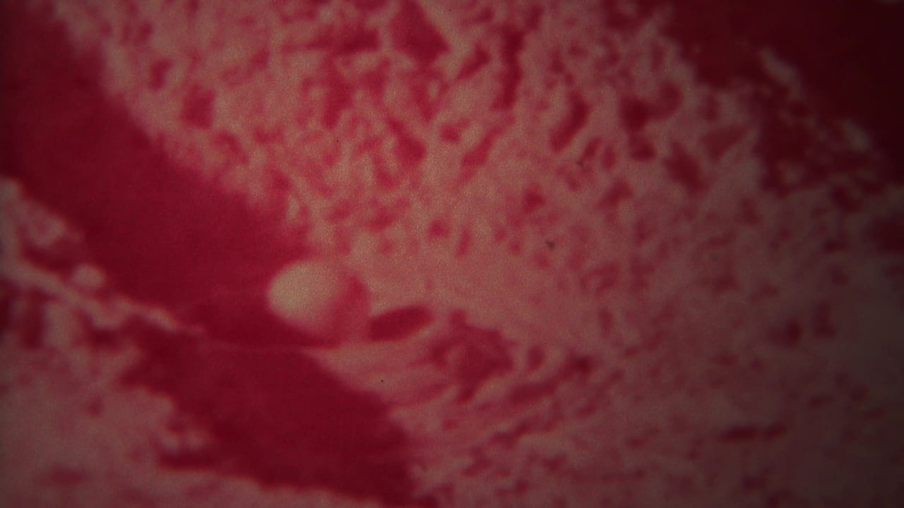 Red-tinted close view of rippled river water with pale highlights and dark shadows.