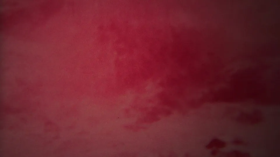 1967 Yellowstone frame showing a soft red-tinted river close-up with shadowed texture, grain, and indistinct motion across the water.