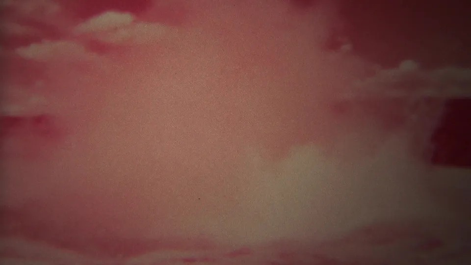 1967 Yellowstone 8mm frame showing a geyser burst of steam and water against a pink-tinged cloudy sky.