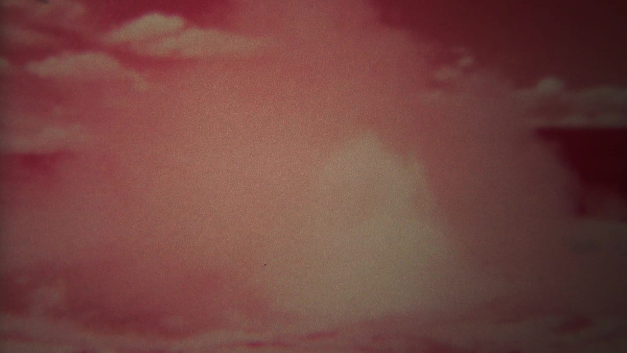 Red-shifted 8mm frame of clouded sky, likely from the 1967 Yellowstone home-movie clip.