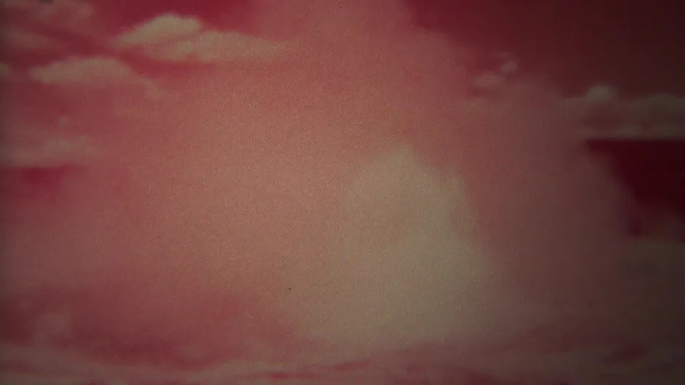 Red-shifted 8mm frame of clouded sky, likely from the 1967 Yellowstone home-movie clip.