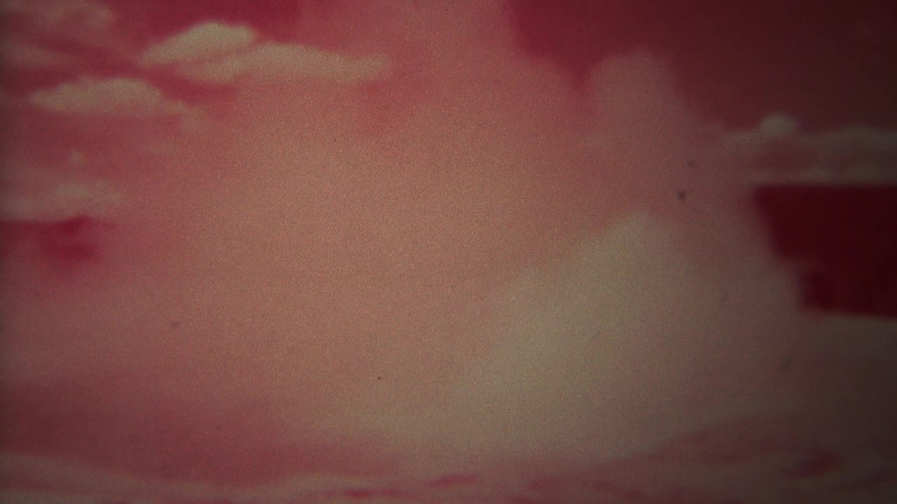 Soft red-tinted sky with pale clouds and a dark shape near the upper right.