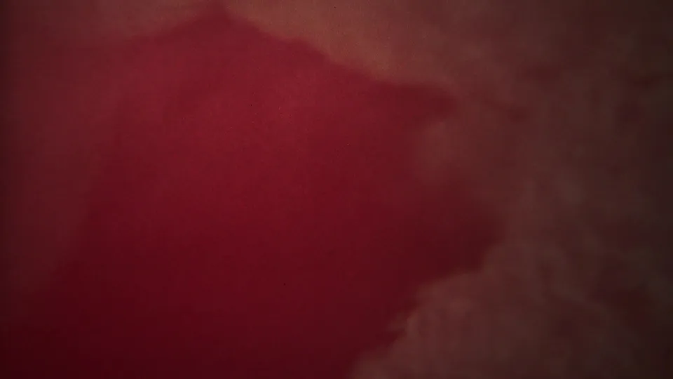 1967 Yellowstone 8mm frame showing reddish haze and a faint vertical steam or spray form, with low contrast and visible film texture.