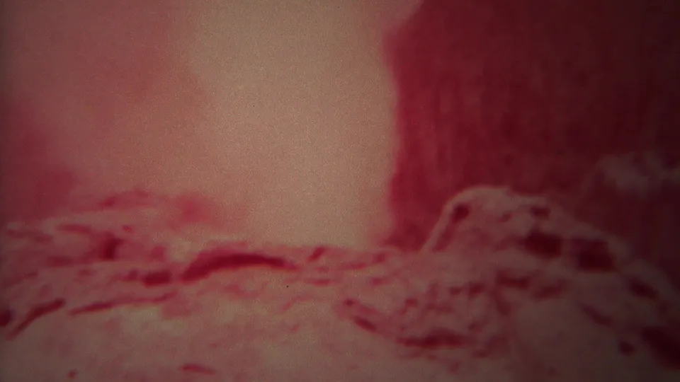 Handheld 1967 Yellowstone frame with soft focus on steam, rock, and mineral ground around Rocket Geyser.