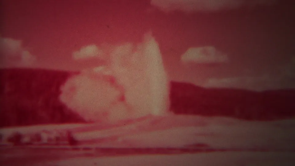 1967 Yellowstone home-movie still showing the geyser eruption continuing, with the viewing area partly visible at the bottom.