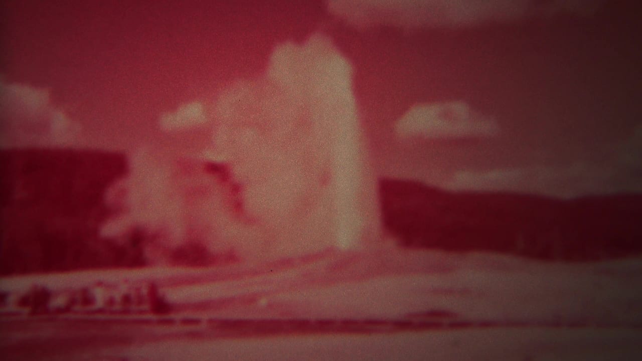 Geyser plume rises high above dark terrain in a red color-shifted frame.