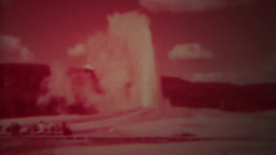 Red-shifted 1967 Yellowstone frame showing Old Faithful's plume with steam drifting across the lower basin.