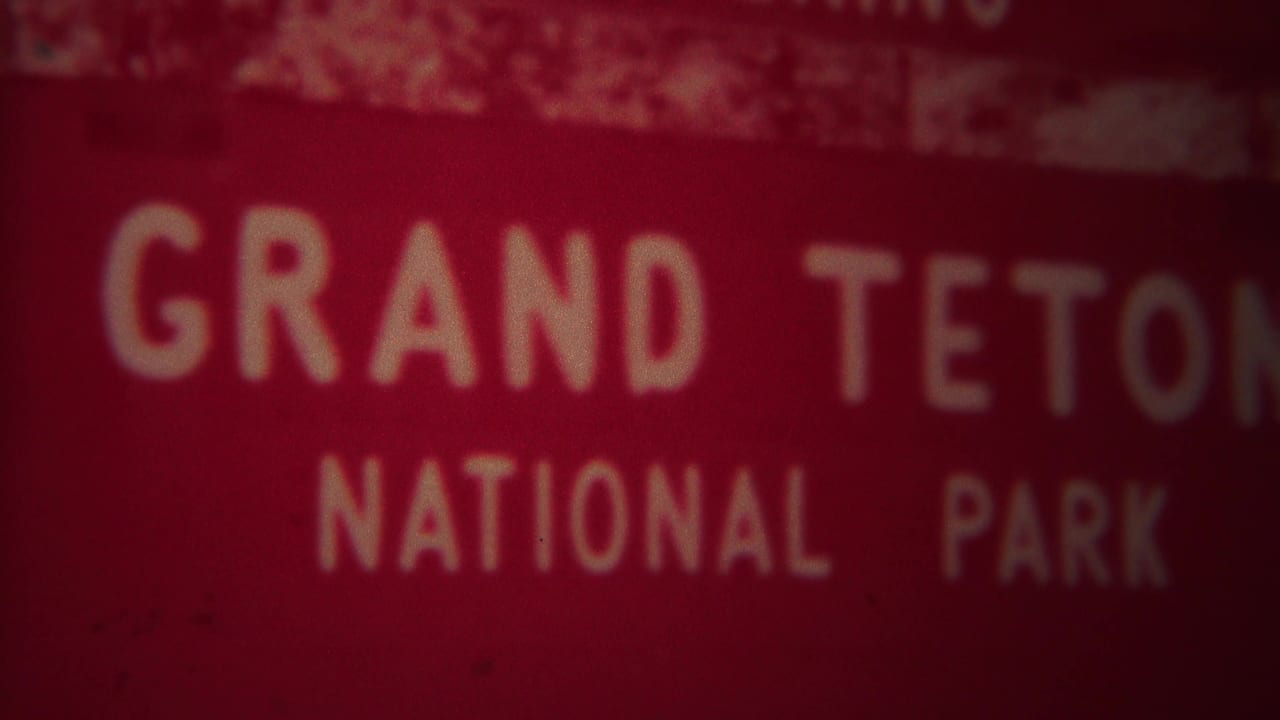 Soft red Grand Teton National Park sign with white lettering.