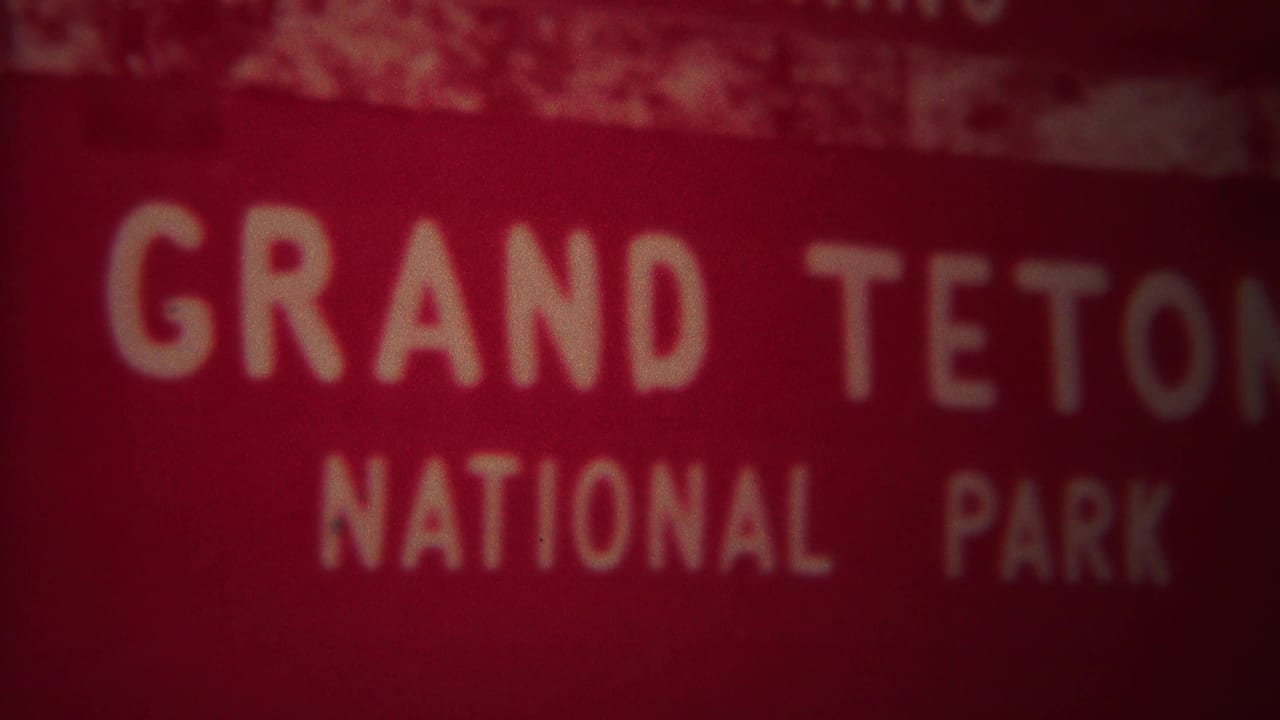 Blurred red Grand Teton National Park sign, partially cropped.