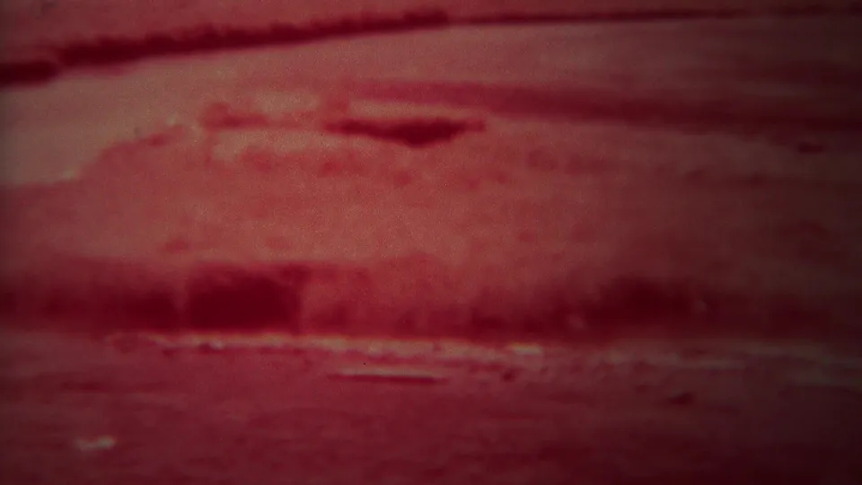 1967 Yellowstone 8mm frame with crimson-toned river water, shadowed bank shapes, and soft low-light reflections.